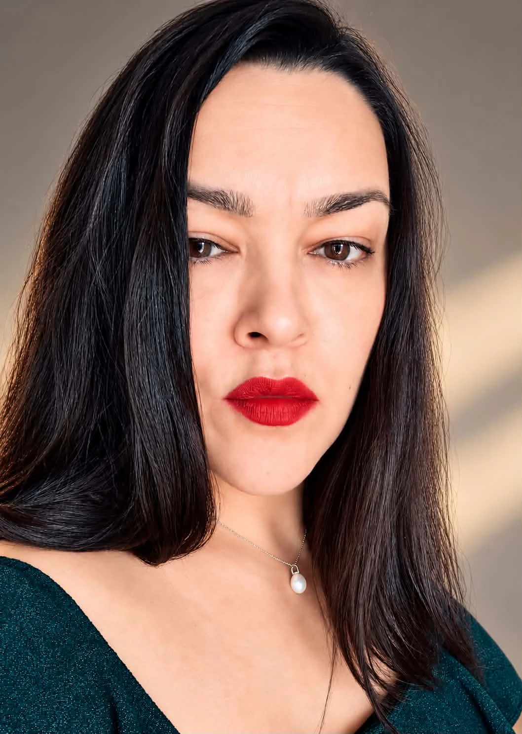 Laura, founder of Soul Bridge, in a colour portrait with dark hair, red lipstick and a pearl necklace